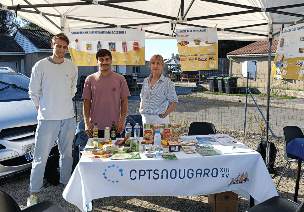 Sur l'image, nous pouvons voir trois professionnels de santé, derrière un stand en trian de regarder l'objectif.